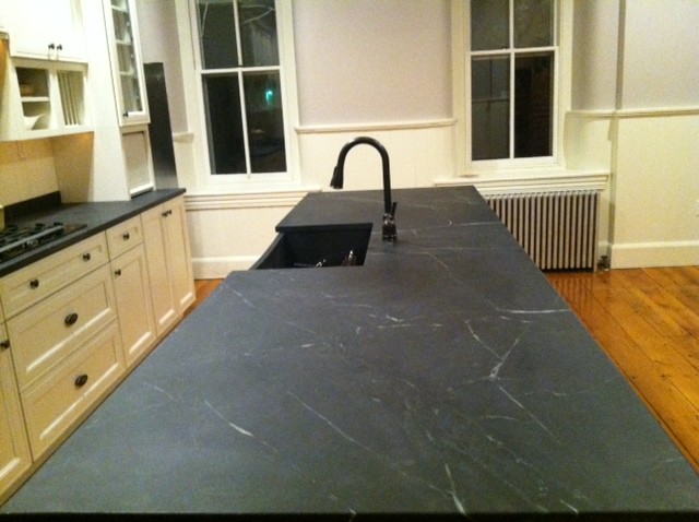 Example of a mid-sized classic u-shaped dark wood floor eat-in kitchen design in Philadelphia with a farmhouse sink, raised-panel cabinets, white cabinets, soapstone countertops, white backsplash, subway tile backsplash, stainless steel appliances and a peninsula