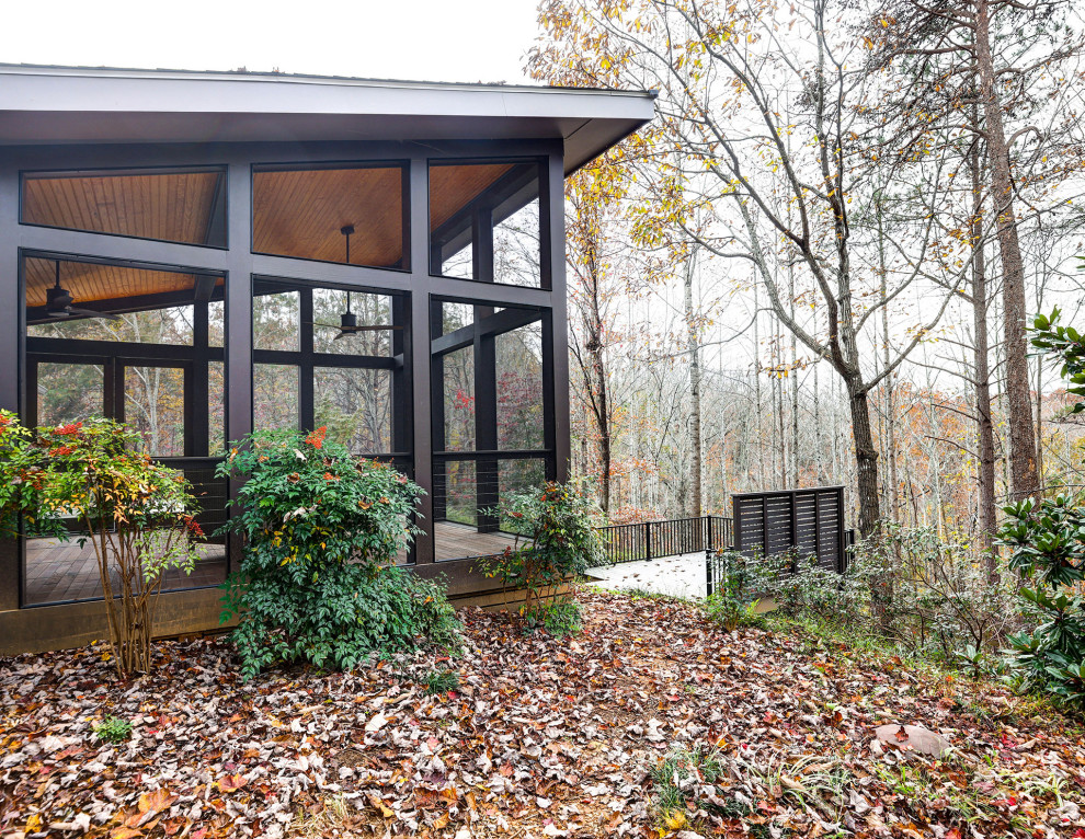 This is an example of a modern screened-in and metal railing back porch design in Other with a roof extension.