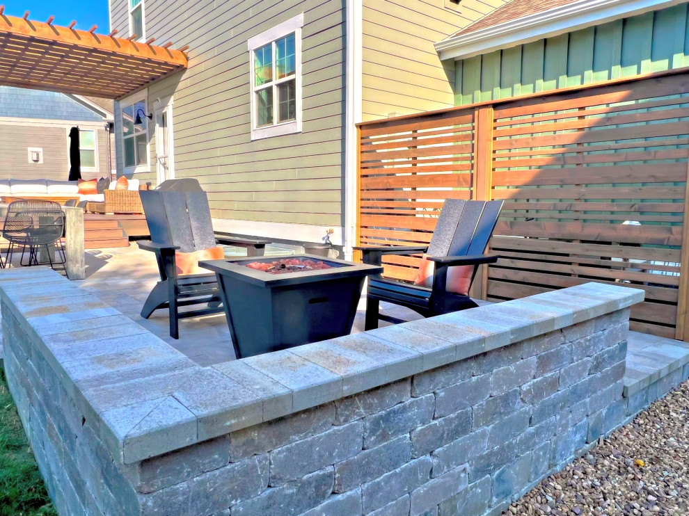 Photo of a mid-sized contemporary backyard patio in Denver with a fire feature, natural stone pavers and a pergola.