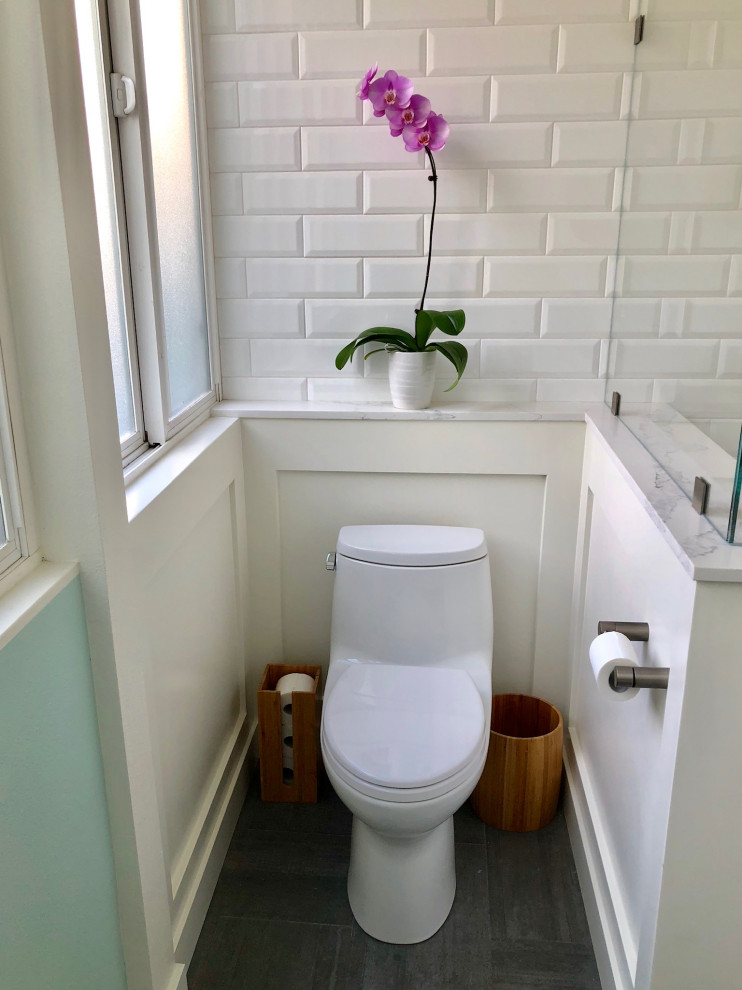 This is an example of a small contemporary cloakroom in Los Angeles with white cabinets, a one-piece toilet, white tiles, ceramic tiles, blue walls, ceramic flooring, marble worktops, grey floors, white worktops and wainscoting.