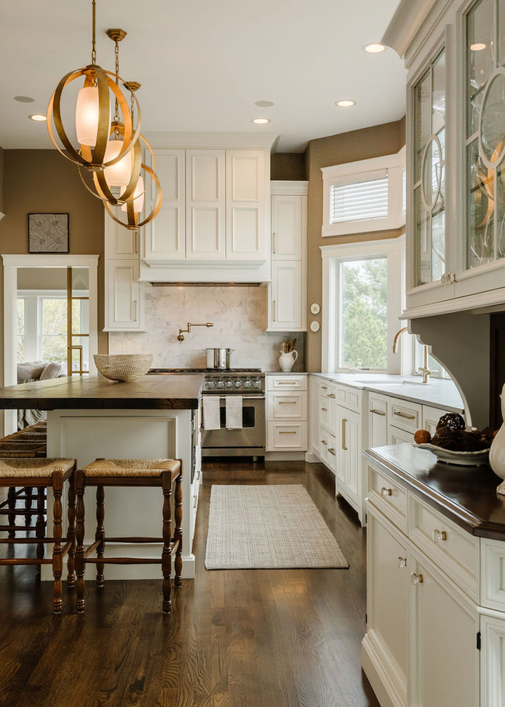 Inspiration for a transitional u-shaped medium tone wood floor and brown floor kitchen remodel with white cabinets, stainless steel appliances, an island, an undermount sink, recessed-panel cabinets, wood countertops, multicolored backsplash, marble backsplash and brown countertops