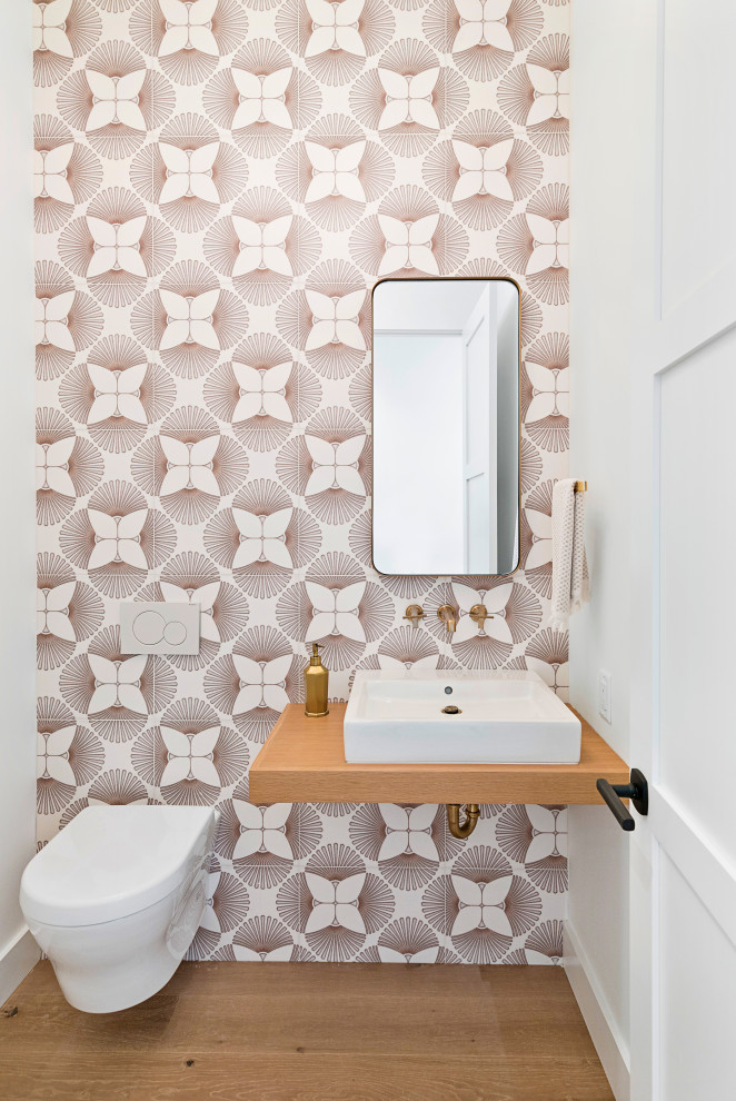 Mid-sized contemporary powder room in San Francisco with a wall-mount toilet, multi-coloured tile, porcelain tile, multi-coloured walls, medium hardwood floors, a vessel sink, wood benchtops, brown floor and brown benchtops.