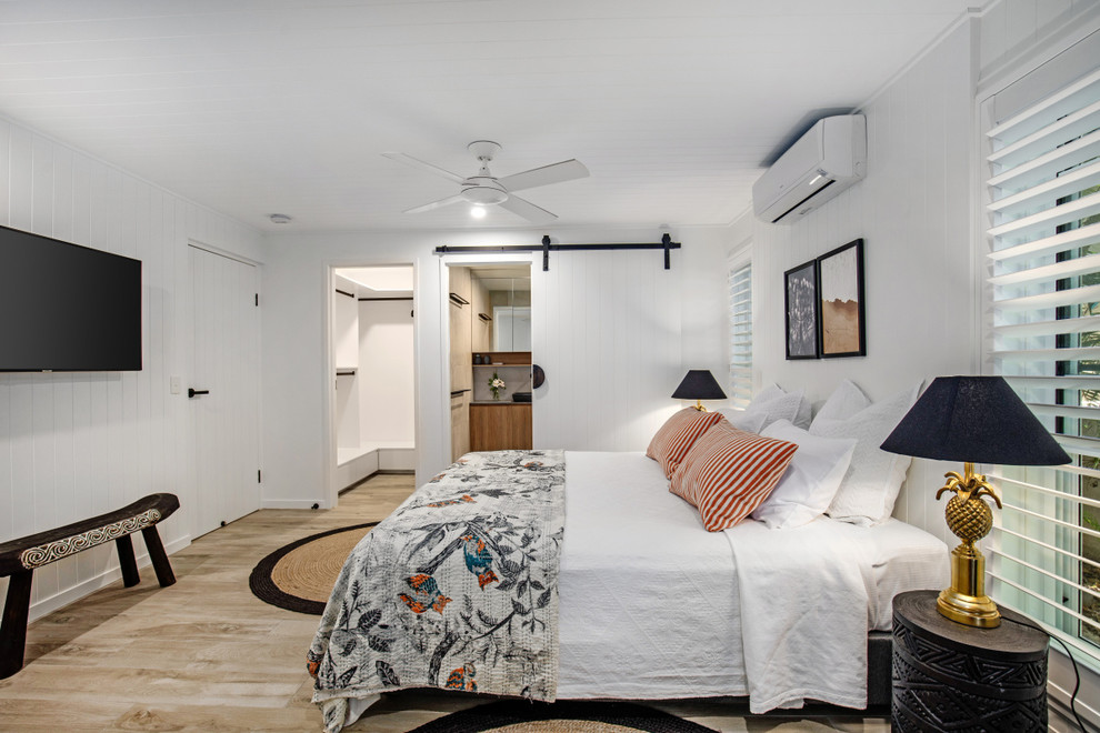 Design ideas for a mid-sized beach style master bedroom in Sunshine Coast with white walls, porcelain floors and grey floor.