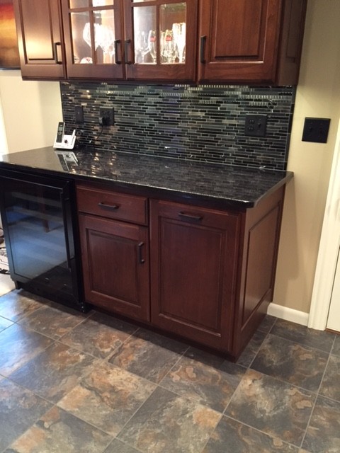 Example of a transitional u-shaped porcelain tile home design design with an undermount sink, medium tone wood cabinets, granite countertops, black backsplash, mosaic tile backsplash, stainless steel appliances and no island