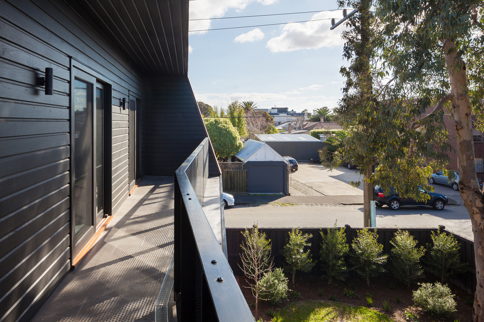 Photo of a mid-sized contemporary two-storey black exterior in Melbourne with wood siding and a gable roof.