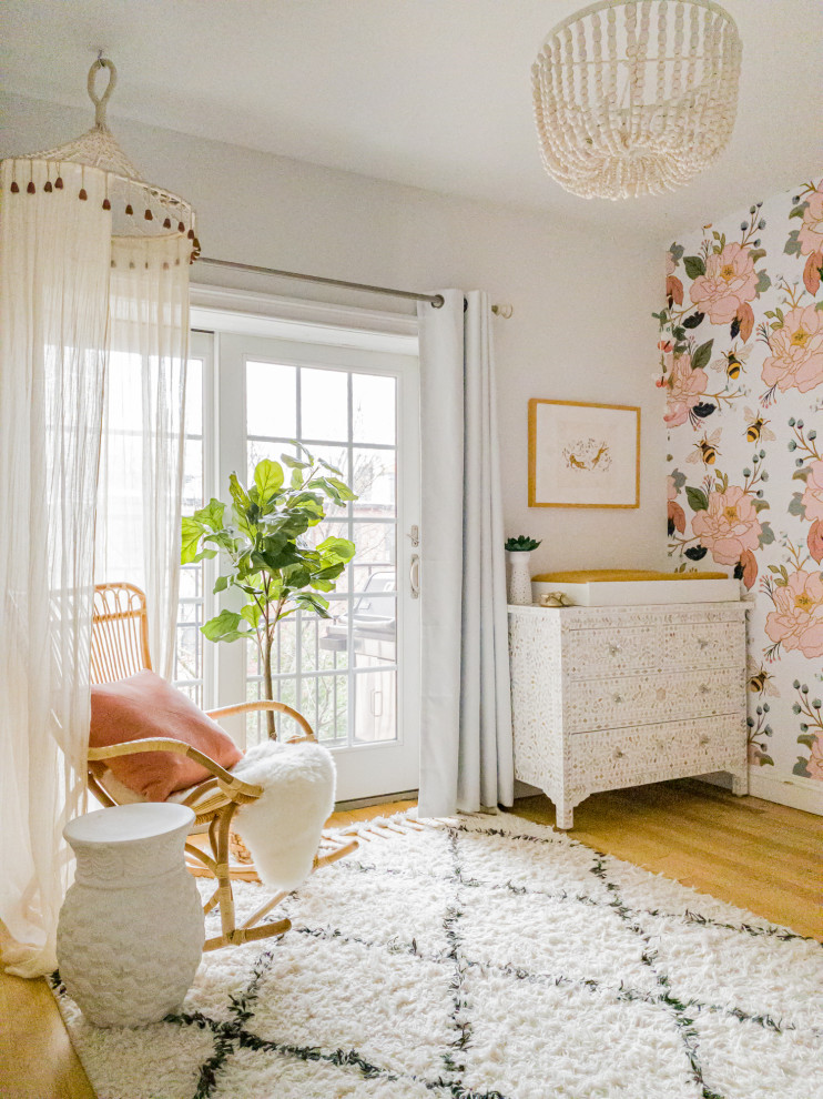 This is an example of a mid-sized eclectic nursery for girls in New York with multi-coloured walls, light hardwood floors, brown floor and wallpaper.