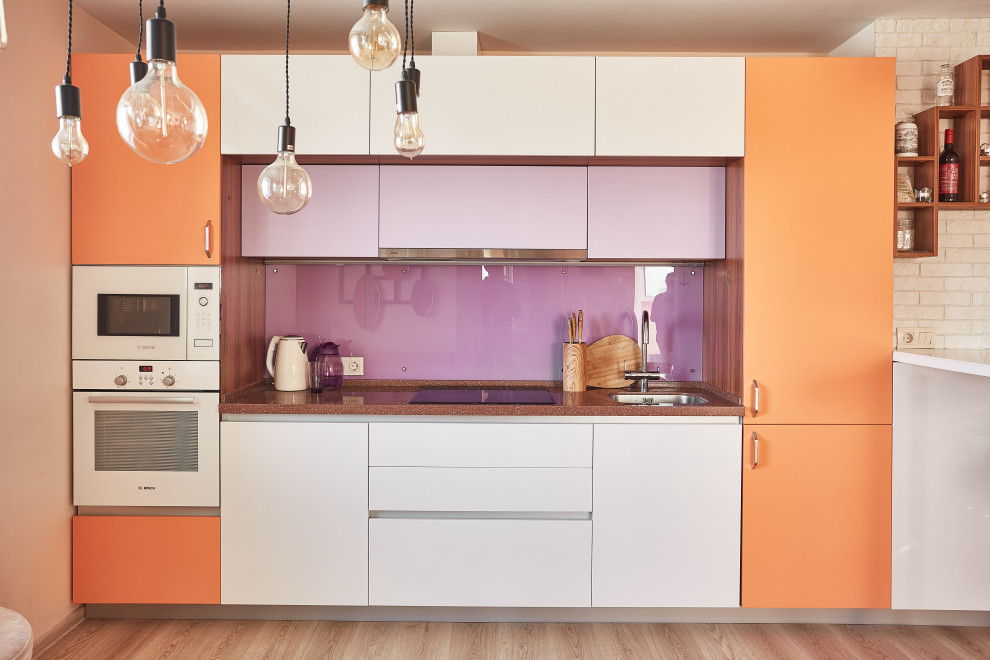 Mid-sized contemporary single-wall eat-in kitchen in Yekaterinburg with a single-bowl sink, flat-panel cabinets, orange cabinets, solid surface benchtops, glass sheet splashback, white appliances, laminate floors, no island, brown floor and brown benchtop.