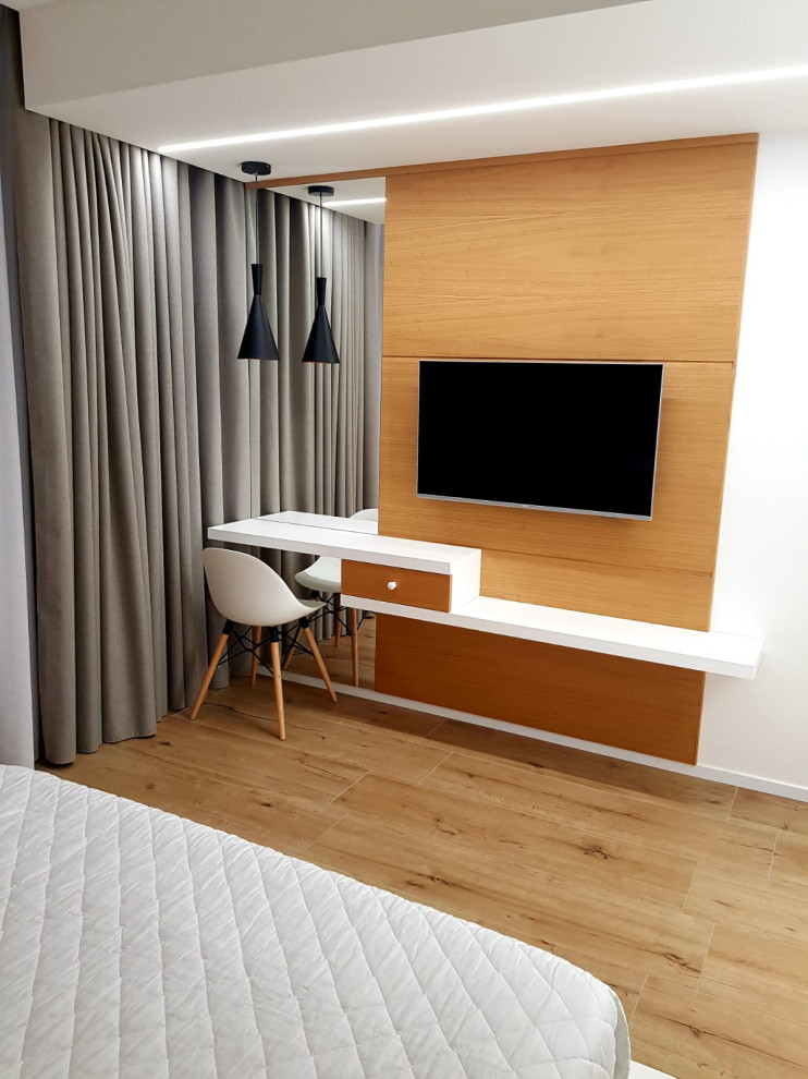 Immagine di una camera matrimoniale minimalista di medie dimensioni con pareti bianche, parquet chiaro e pavimento marrone