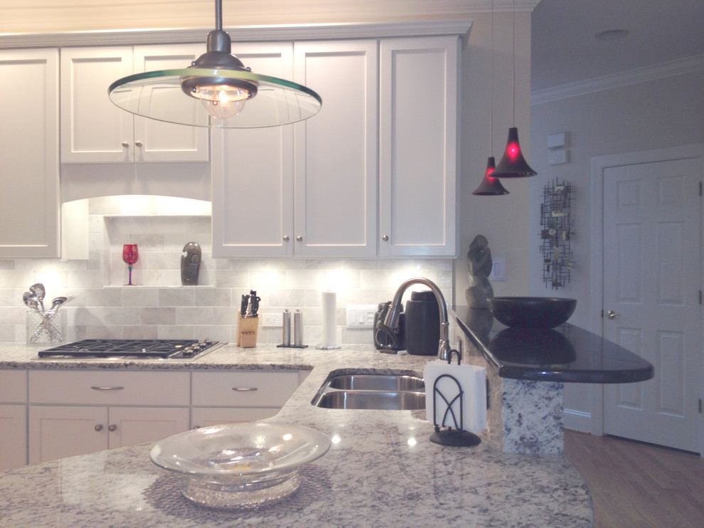 Inspiration for a mid-sized transitional l-shaped light wood floor eat-in kitchen remodel with an undermount sink, recessed-panel cabinets, white cabinets, granite countertops, white backsplash, stone tile backsplash, white appliances and a peninsula