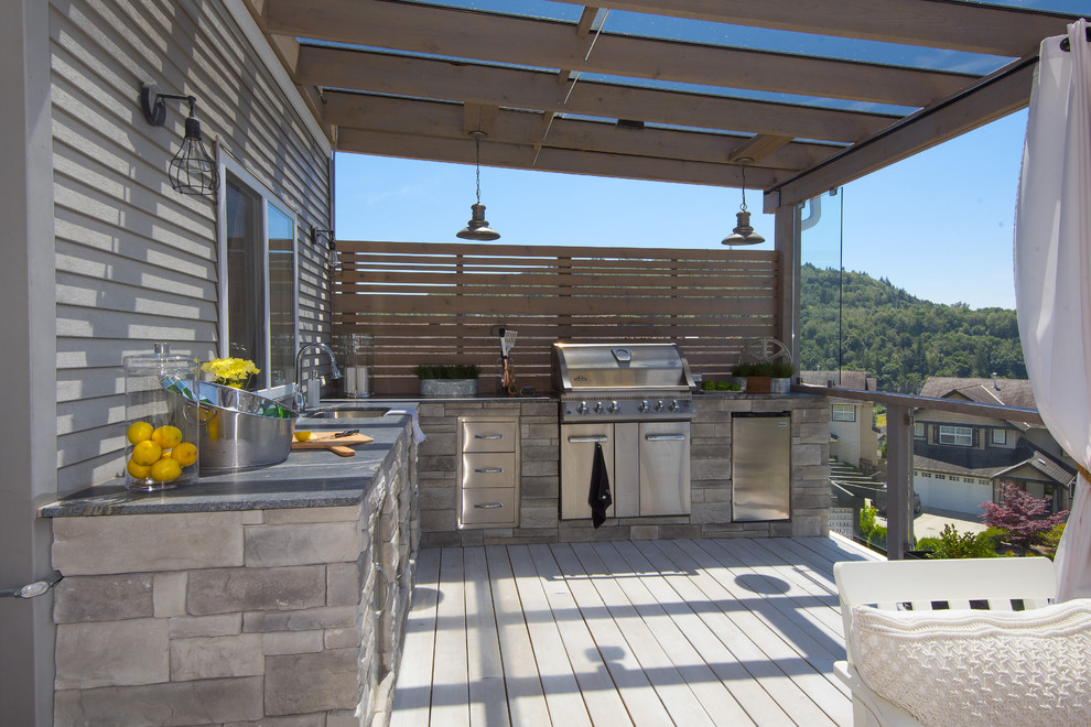 Example of a large transitional backyard outdoor kitchen deck design in Vancouver with a pergola