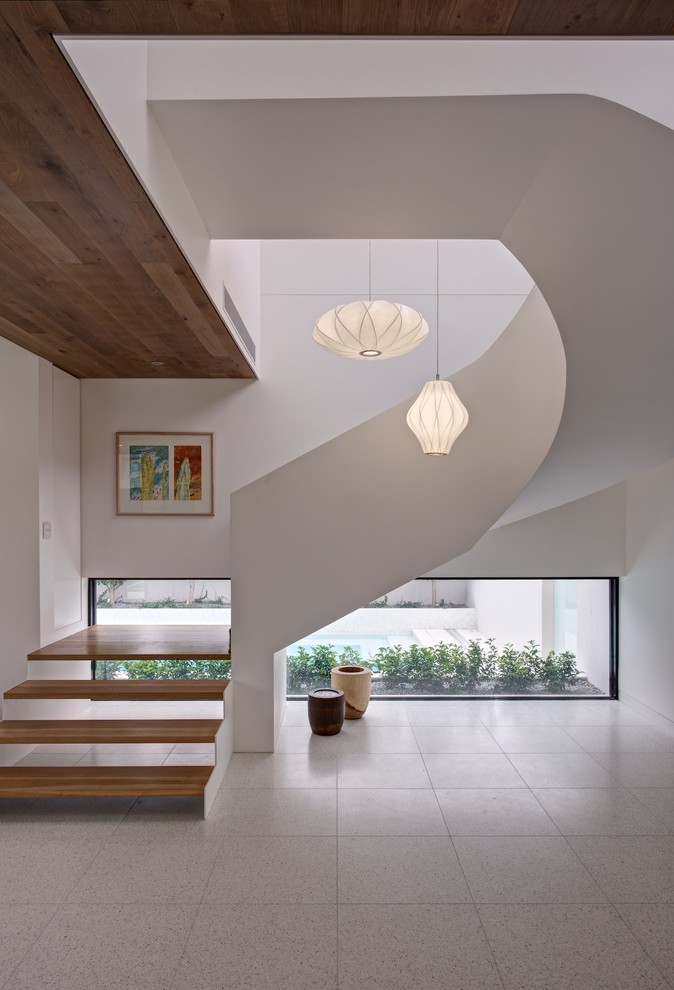 Photo of a large contemporary wood curved staircase in Melbourne with open risers.