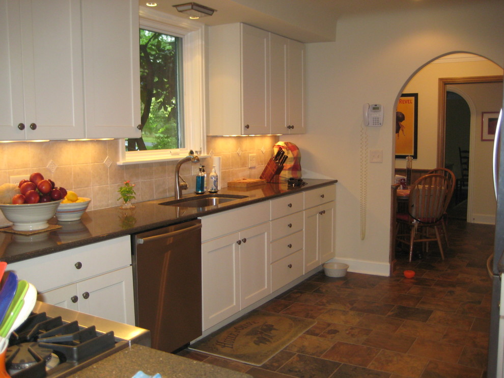 This is an example of a small traditional galley separate kitchen in Cincinnati with an undermount sink, shaker cabinets, white cabinets, quartz benchtops, beige splashback, stone tile splashback, stainless steel appliances, slate floors and no island.