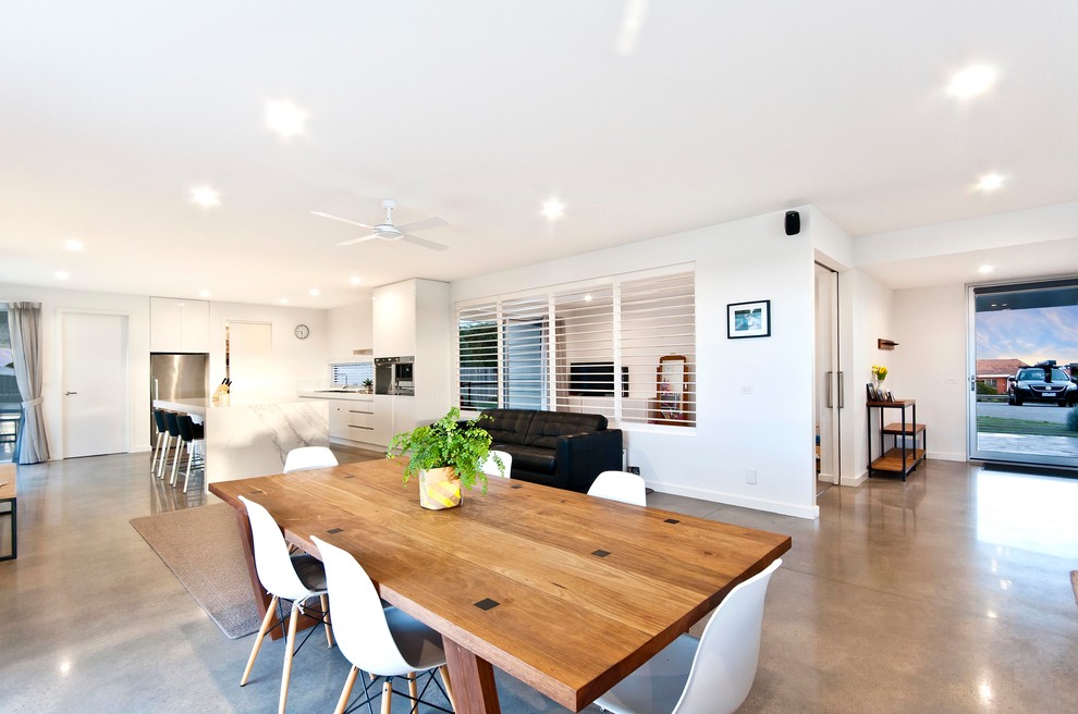 Photo of a large modern kitchen/dining combo in Melbourne with white walls and concrete floors.