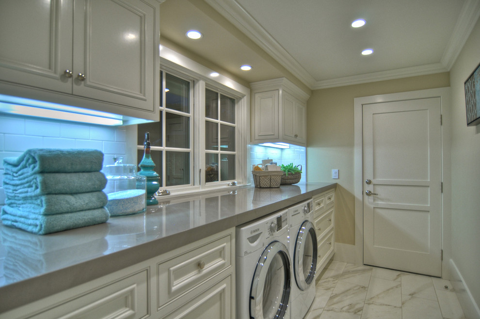 Design ideas for a beach style laundry room in Los Angeles with white cabinets, white floor and grey benchtop.
