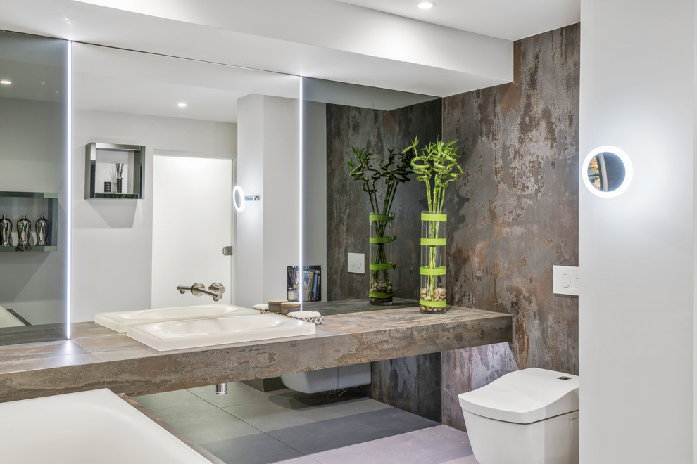 Inspiration for a large tropical wet room bathroom in West Midlands with glass-front cabinets, a drop-in tub, a wall-mount toilet, white walls, concrete floors, with a sauna, an integrated sink, solid surface benchtops, grey floor, a sliding shower screen and multi-coloured benchtops.