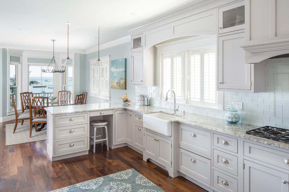 This is an example of a beach style kitchen in Other with a farmhouse sink, beaded inset cabinets, grey cabinets, blue splashback, subway tile splashback, dark hardwood floors, a peninsula and brown floor.
