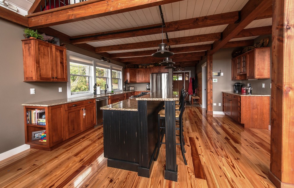 Inspiration for a large country l-shaped eat-in kitchen in Portland Maine with an undermount sink, flat-panel cabinets, medium wood cabinets, stainless steel appliances, granite benchtops, light hardwood floors and with island.
