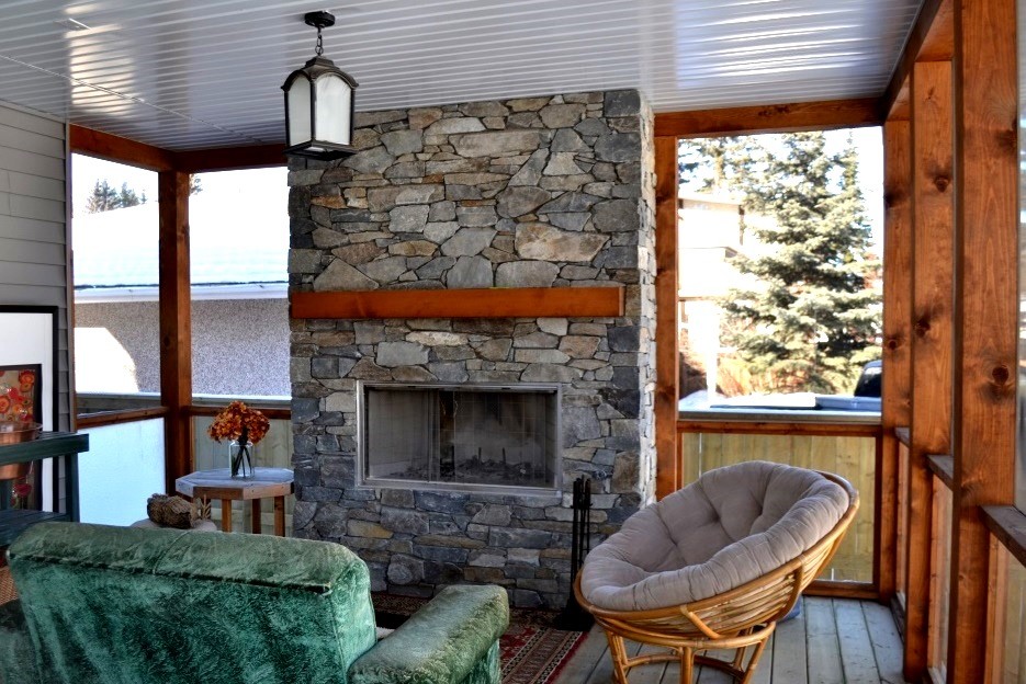 Design ideas for a mid-sized country sunroom in Calgary with light hardwood floors, a standard fireplace, a stone fireplace surround, a standard ceiling and grey floor.