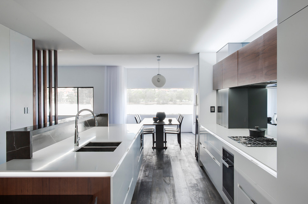 Photo of a mid-sized contemporary eat-in kitchen in Sydney with an undermount sink, medium wood cabinets, solid surface benchtops, mirror splashback, stainless steel appliances, dark hardwood floors and with island.