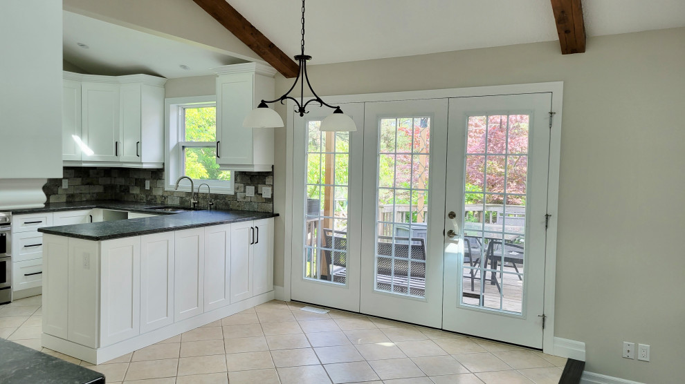 Open concept kitchen - transitional u-shaped open concept kitchen idea with an undermount sink, recessed-panel cabinets, white cabinets, multicolored backsplash, stone tile backsplash, stainless steel appliances and a peninsula