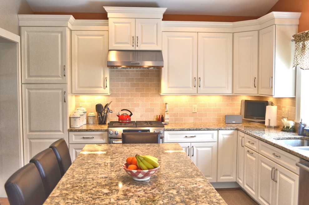 Enclosed kitchen - large transitional l-shaped medium tone wood floor enclosed kitchen idea in Columbus with an undermount sink, raised-panel cabinets, white cabinets, granite countertops, beige backsplash, stone tile backsplash, stainless steel appliances and an island