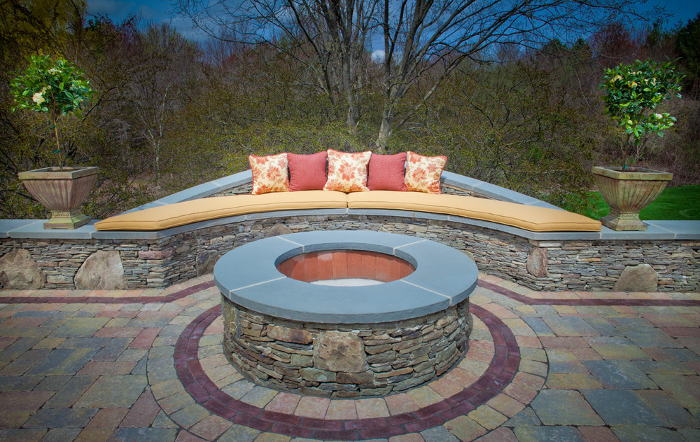 Inspiration for a mid-sized traditional backyard patio in Boston with a fire feature, natural stone pavers and no cover.