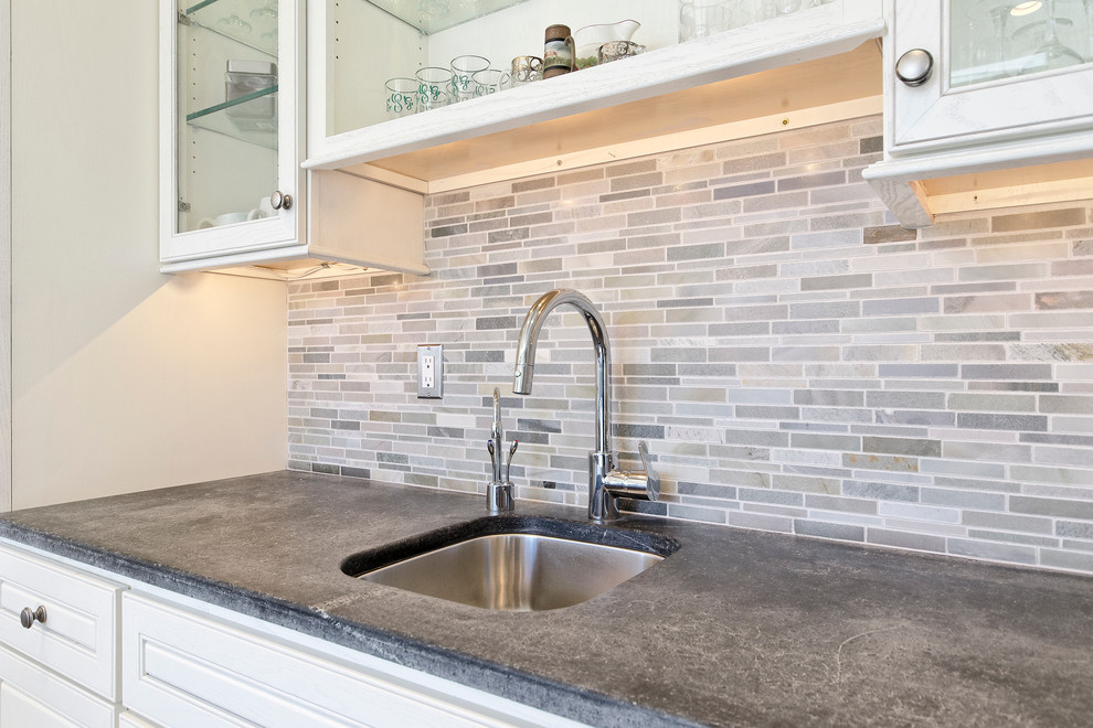 Example of a transitional u-shaped open concept kitchen design with a farmhouse sink, raised-panel cabinets, white cabinets, soapstone countertops, multicolored backsplash and stainless steel appliances
