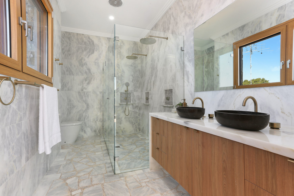 Contemporary bathroom in Sydney with flat-panel cabinets, medium wood cabinets, a curbless shower, gray tile, a vessel sink, grey floor, a hinged shower door, white benchtops, a double vanity and a floating vanity.