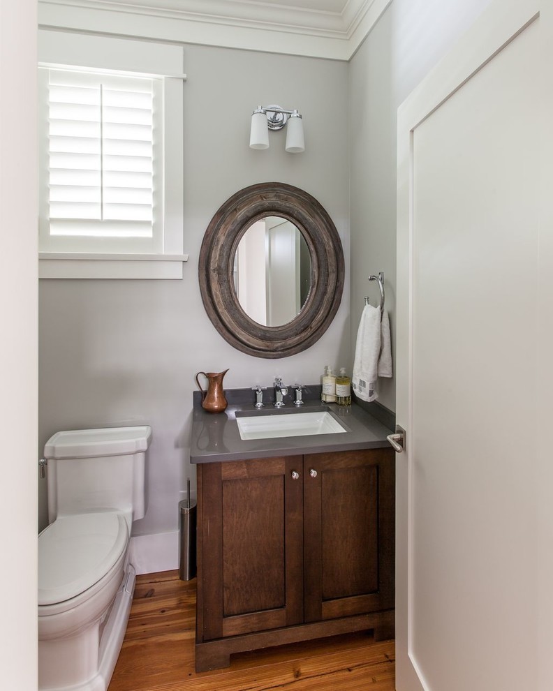 Inspiration for a large traditional powder room in Vancouver with an undermount sink, dark wood cabinets, a one-piece toilet, grey walls, medium hardwood floors, recessed-panel cabinets and grey benchtops.