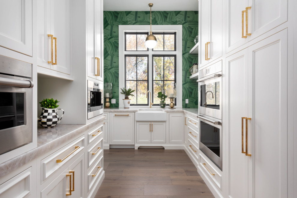Design ideas for a large traditional u-shaped kitchen pantry in St Louis with recessed-panel cabinets, white cabinets, quartz worktops, integrated appliances, medium hardwood flooring, an island and brown floors.