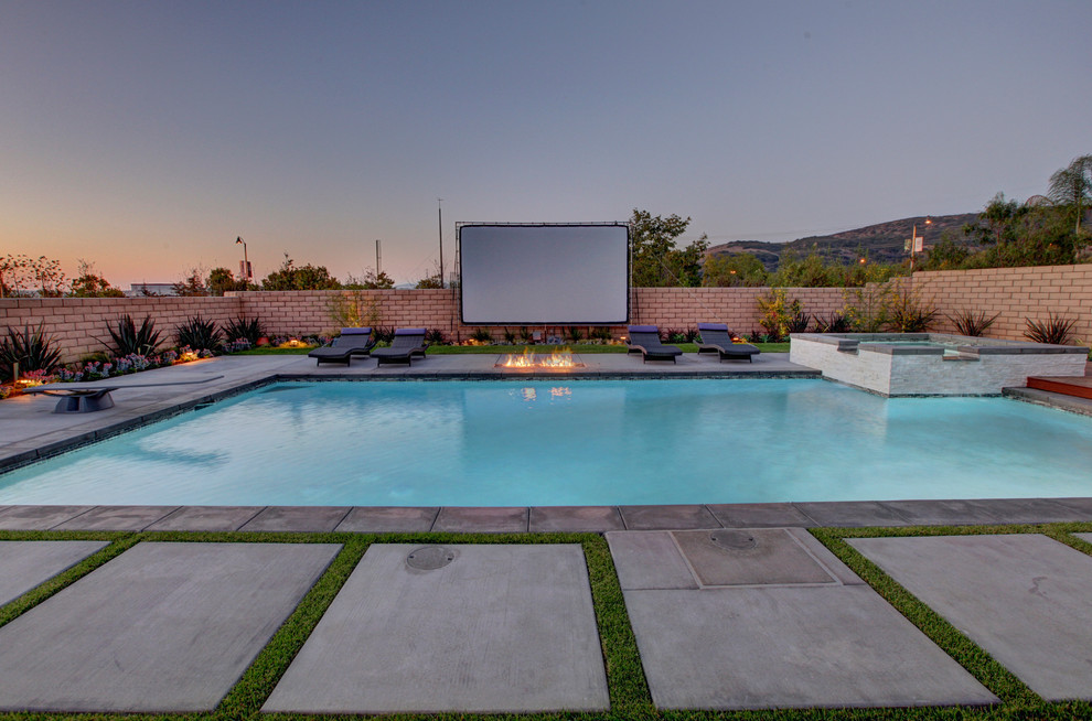 Photo of a large contemporary backyard rectangular lap pool in Orange County with concrete slab and a hot tub.