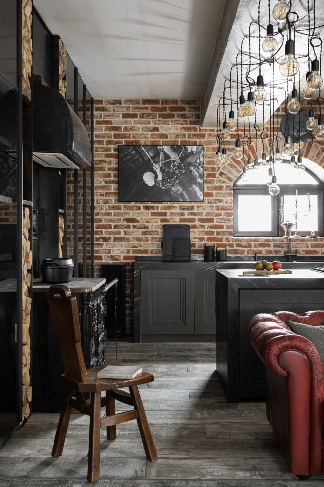 Bild på ett mellanstort funkis svart svart kök, med en dubbel diskho, grå skåp, marmorbänkskiva, rött stänkskydd, stänkskydd i metallkakel, svarta vitvaror, en köksö och grått golv