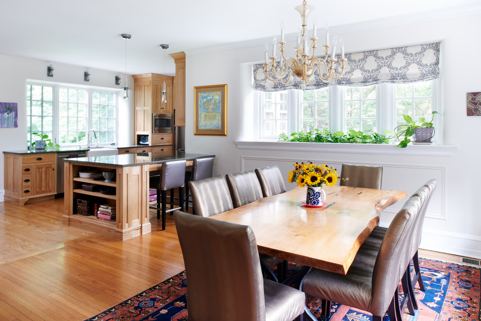 Esempio di una grande sala da pranzo aperta verso la cucina american style con pareti bianche, pavimento in legno massello medio e pavimento marrone