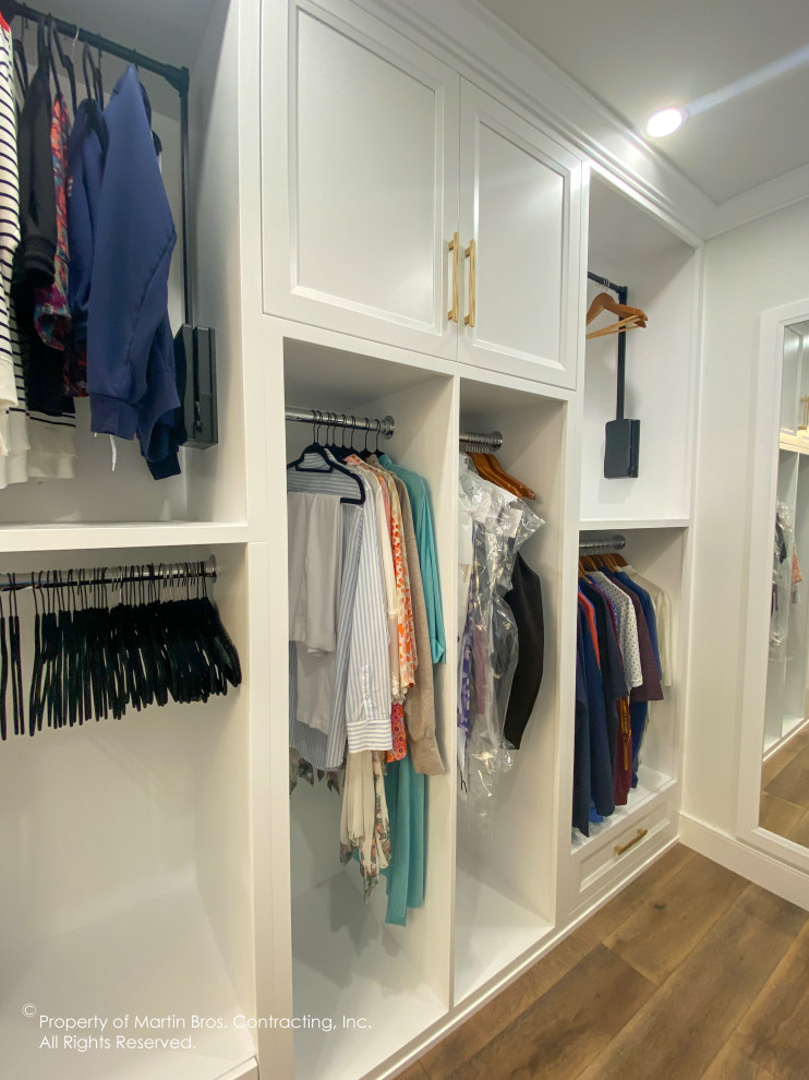 Walk-in closet - large transitional gender-neutral medium tone wood floor walk-in closet idea with recessed-panel cabinets and white cabinets