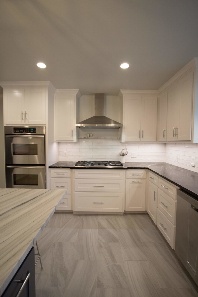 Enclosed kitchen - mid-sized transitional l-shaped ceramic tile and gray floor enclosed kitchen idea in Dallas with an undermount sink, shaker cabinets, white cabinets, soapstone countertops, white backsplash, stone tile backsplash, stainless steel appliances and an island