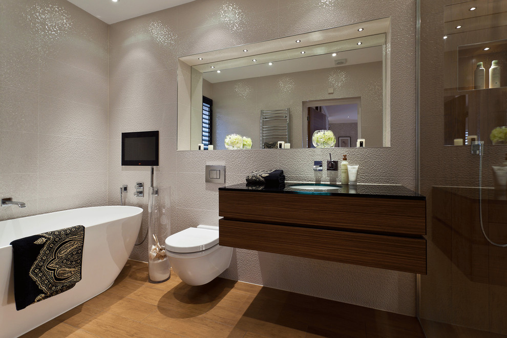 Contemporary bathroom in London with an undermount sink, flat-panel cabinets, dark wood cabinets, a freestanding tub, a wall-mount toilet and white tile.