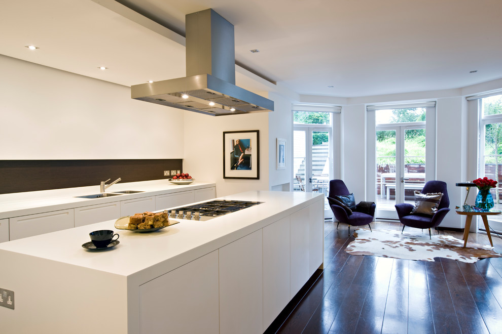 Design ideas for a mid-sized contemporary single-wall kitchen in London with a double-bowl sink, flat-panel cabinets, white cabinets, brown splashback, stainless steel appliances, dark hardwood floors, with island, brown floor and white benchtop.