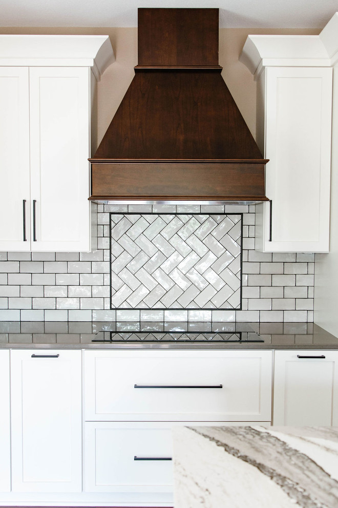Mid-sized transitional l-shaped medium tone wood floor and brown floor eat-in kitchen photo in Omaha with a farmhouse sink, shaker cabinets, white cabinets, quartzite countertops, white backsplash, subway tile backsplash, stainless steel appliances, an island and white countertops