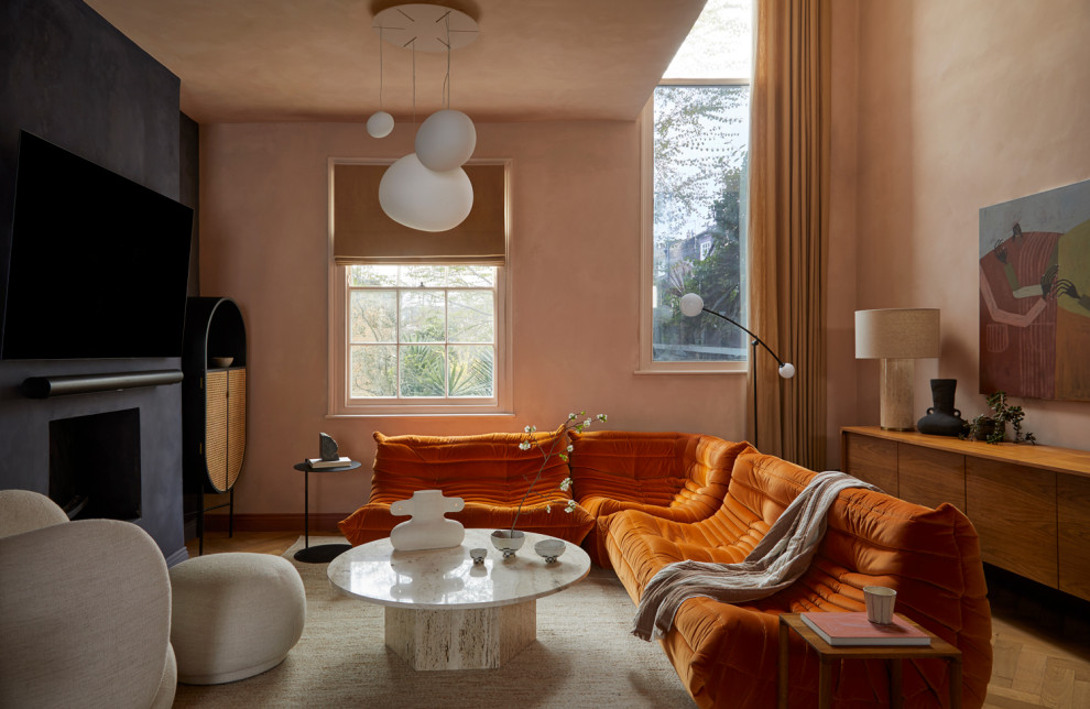 Small contemporary open plan living room in London with orange walls, medium hardwood flooring, a plastered fireplace surround and a wall mounted tv.