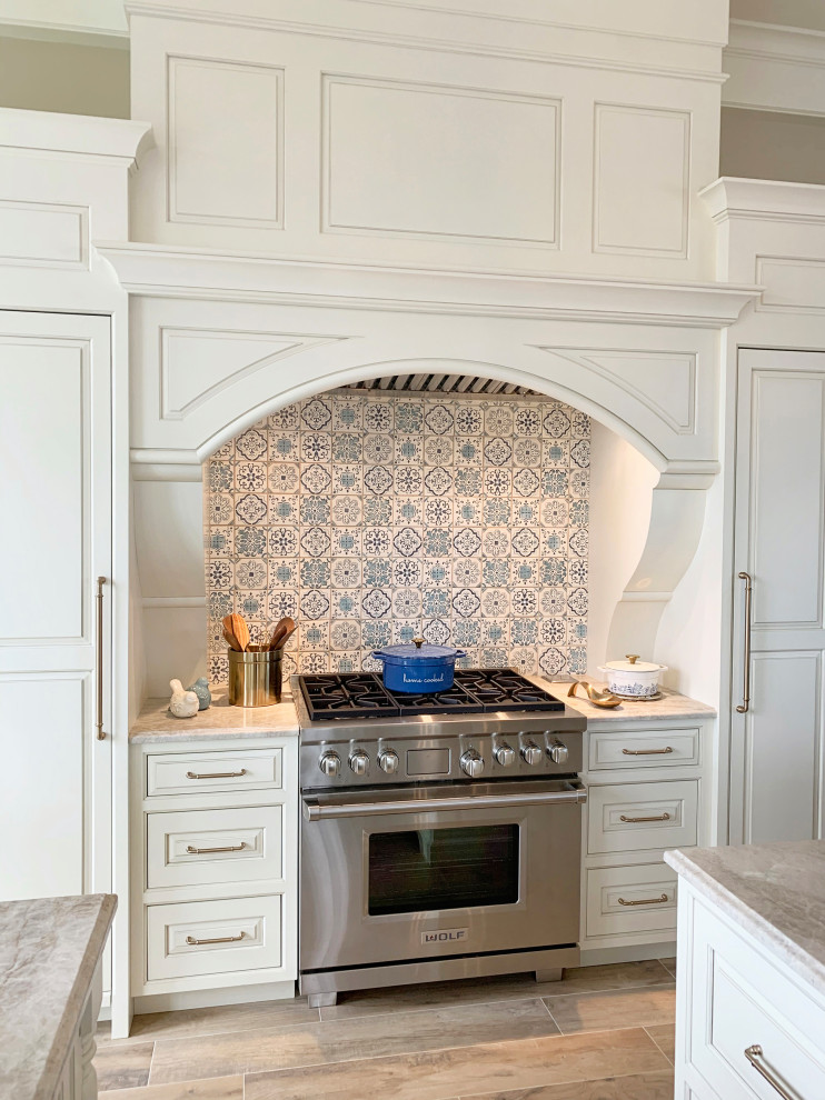 グランドラピッズにあるシャビーシック調のおしゃれなキッチン (インセット扉のキャビネット、白いキャビネット、クオーツストーンカウンター、青いキッチンパネル、シルバーの調理設備、淡色無垢フローリング、ベージュの床、ベージュのキッチンカウンター) の写真