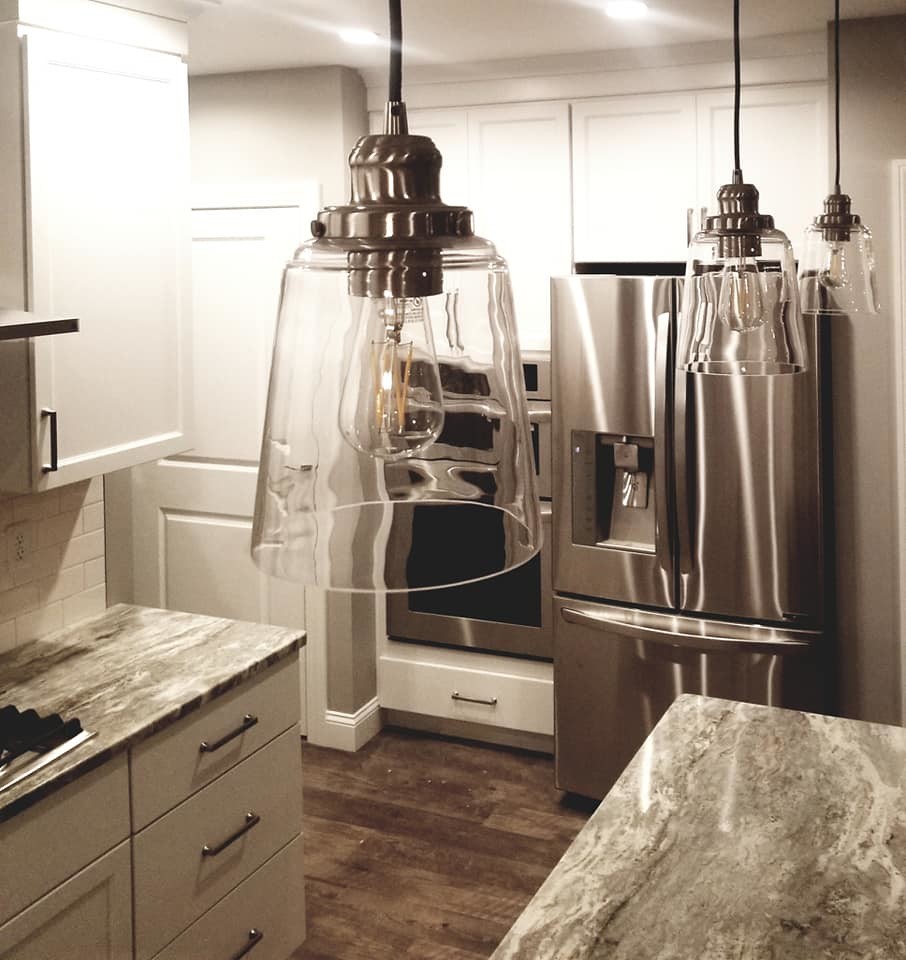 Example of a transitional brown floor kitchen design with an undermount sink, flat-panel cabinets, white cabinets, quartzite countertops, white backsplash, subway tile backsplash, stainless steel appliances and an island