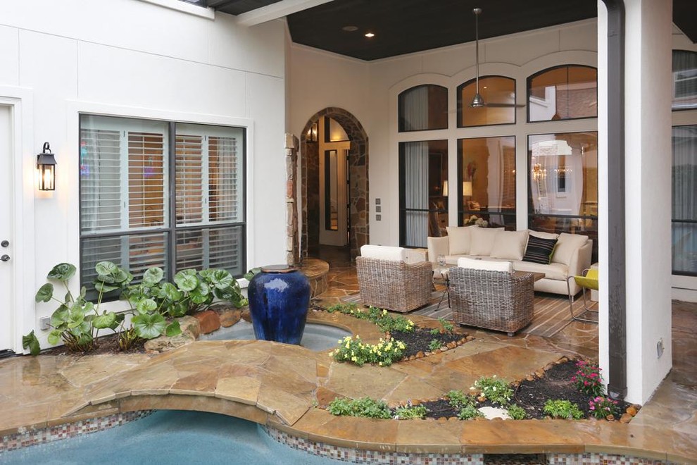 Photo of a large eclectic backyard patio in Houston with a water feature, natural stone pavers and a roof extension.