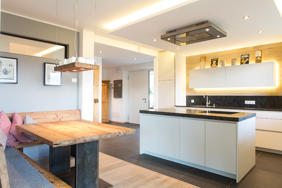 This is an example of a large country single-wall open plan kitchen in Other with flat-panel cabinets, white cabinets, black splashback and with island.