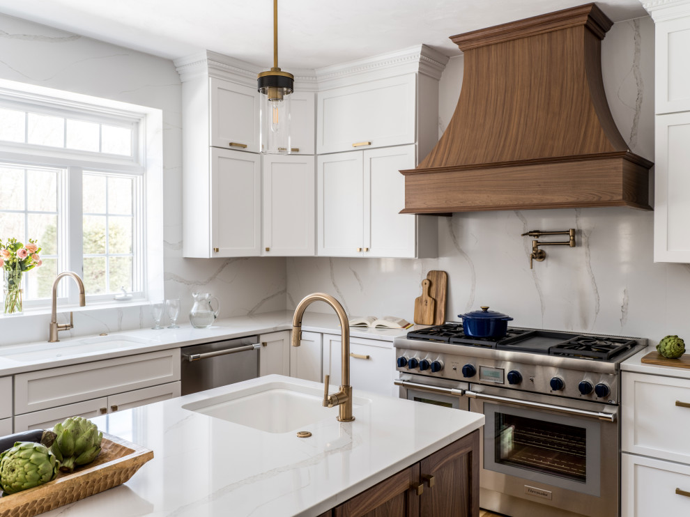 Inspiration for a transitional u-shaped kitchen in Providence with an undermount sink, recessed-panel cabinets, white cabinets, quartz benchtops, white splashback, engineered quartz splashback, stainless steel appliances, medium hardwood floors, with island, brown floor and white benchtop.