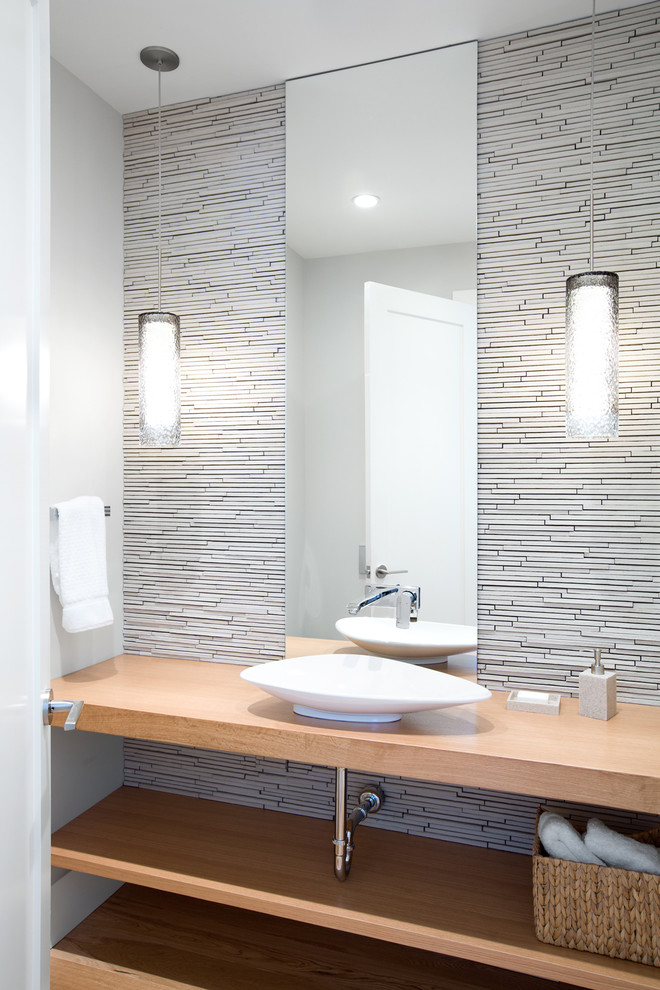 This is an example of a contemporary powder room in Vancouver with a vessel sink, open cabinets, light wood cabinets, wood benchtops, white tile, matchstick tile, white walls and beige benchtops.