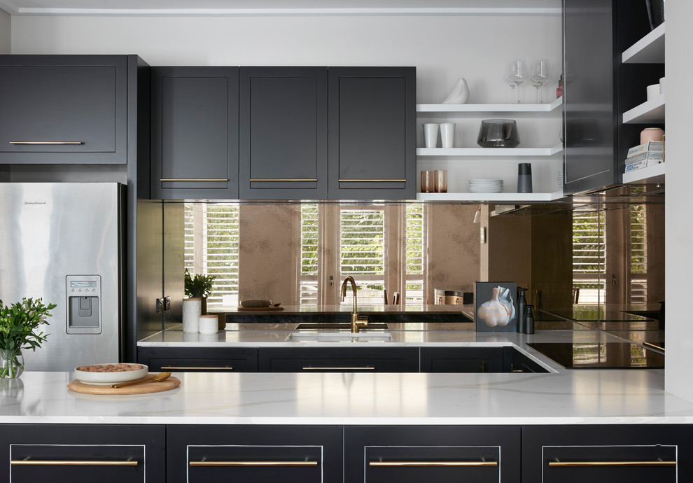 Photo of a large contemporary u-shaped kitchen in Melbourne with black cabinets, marble benchtops, metallic splashback, a double-bowl sink, raised-panel cabinets, glass tile splashback, coloured appliances, plywood floors, with island, brown floor and white benchtop.
