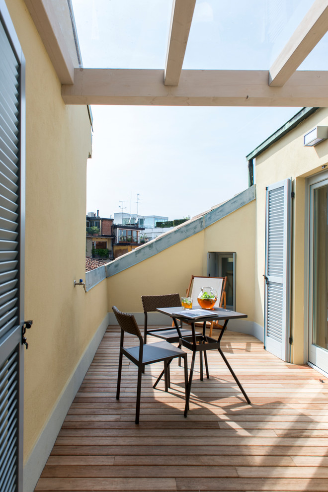 Photo of a small traditional side yard deck in Milan with a pergola.