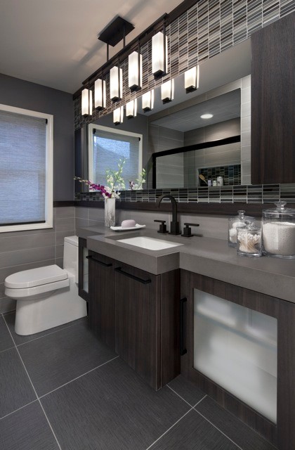 Mid-sized contemporary bathroom in Detroit with an undermount sink, flat-panel cabinets, dark wood cabinets, concrete benchtops, an alcove tub, a one-piece toilet, gray tile, porcelain tile, grey walls and porcelain floors.