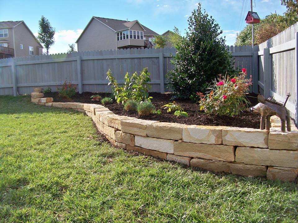 Inspiration for a mid-sized traditional front yard full sun formal garden for spring in Kansas City with natural stone pavers and a retaining wall.