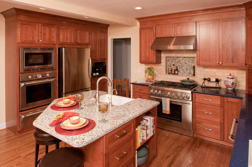 Example of a large transitional medium tone wood floor kitchen design in Nashville with an undermount sink, shaker cabinets, medium tone wood cabinets, recycled glass countertops, beige backsplash, subway tile backsplash, stainless steel appliances and an island